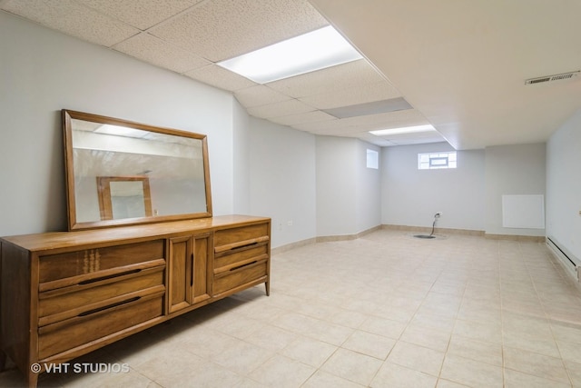 below grade area with baseboards, visible vents, and a drop ceiling