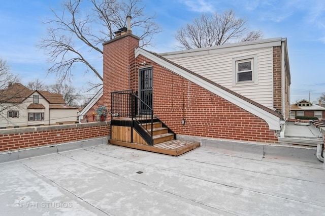 rear view of house with a chimney and brick siding