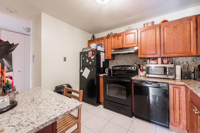 kitchen featuring black appliances, light tile patterned flooring, light stone counters, and tasteful backsplash