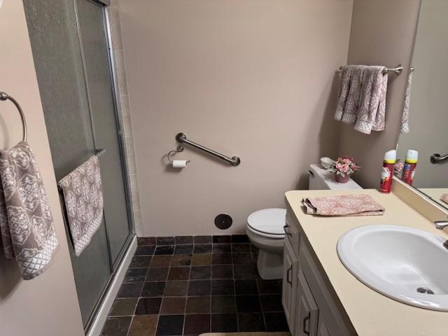 bathroom featuring tile patterned flooring, a shower with door, vanity, and toilet