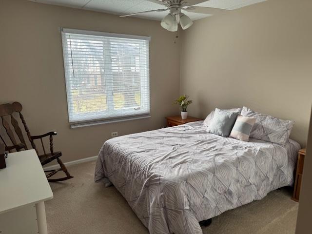 bedroom with light colored carpet, multiple windows, and ceiling fan