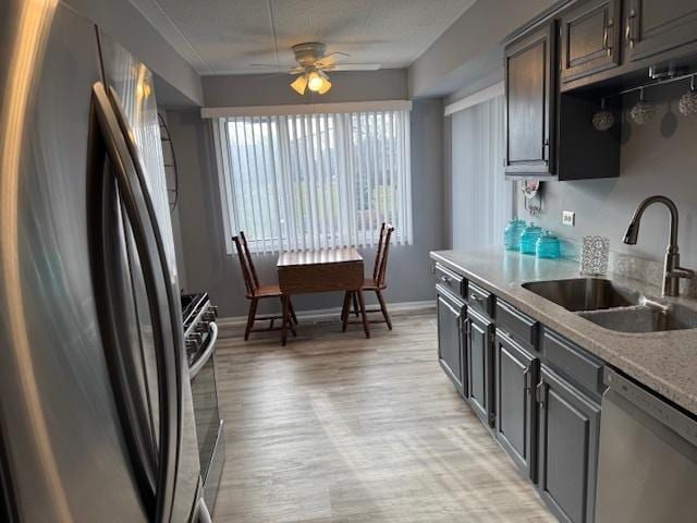 kitchen with appliances with stainless steel finishes, light wood-type flooring, dark brown cabinets, ceiling fan, and sink