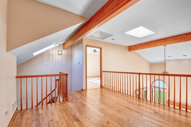 bonus room with vaulted ceiling with skylight and light wood-type flooring