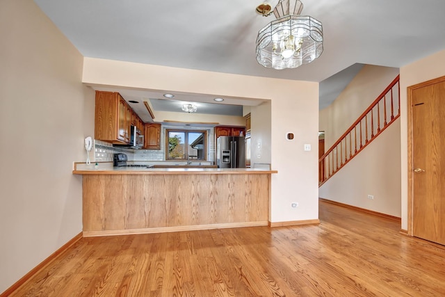 kitchen with kitchen peninsula, appliances with stainless steel finishes, and light hardwood / wood-style flooring