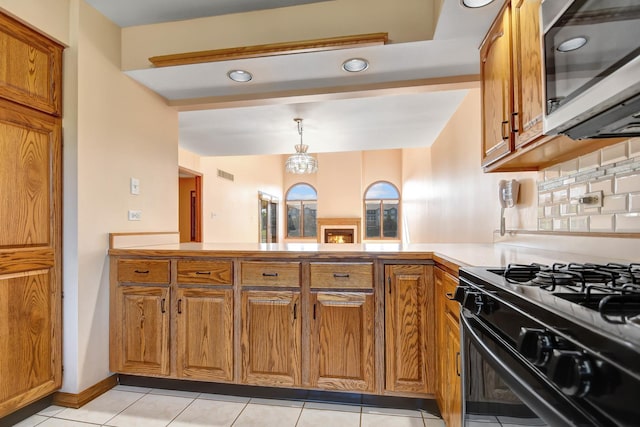 kitchen featuring black range oven, decorative backsplash, light tile patterned floors, and pendant lighting