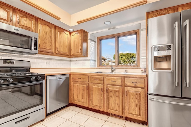 kitchen featuring tasteful backsplash, sink, light tile patterned floors, and stainless steel appliances