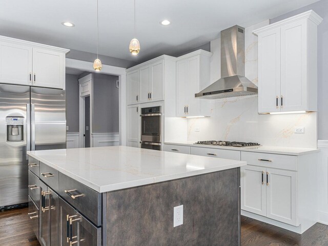 kitchen with white cabinetry, pendant lighting, stainless steel appliances, and wall chimney range hood