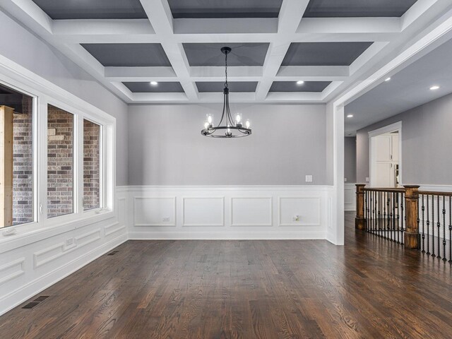 unfurnished dining area featuring beamed ceiling, a notable chandelier, dark wood-type flooring, and coffered ceiling