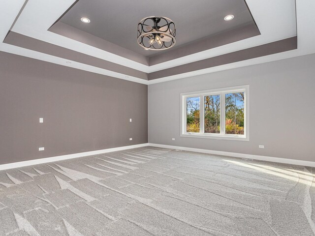 unfurnished room with carpet, a notable chandelier, and a tray ceiling