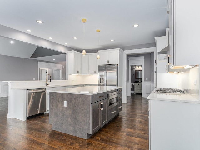 kitchen with a center island, stainless steel appliances, kitchen peninsula, pendant lighting, and white cabinets