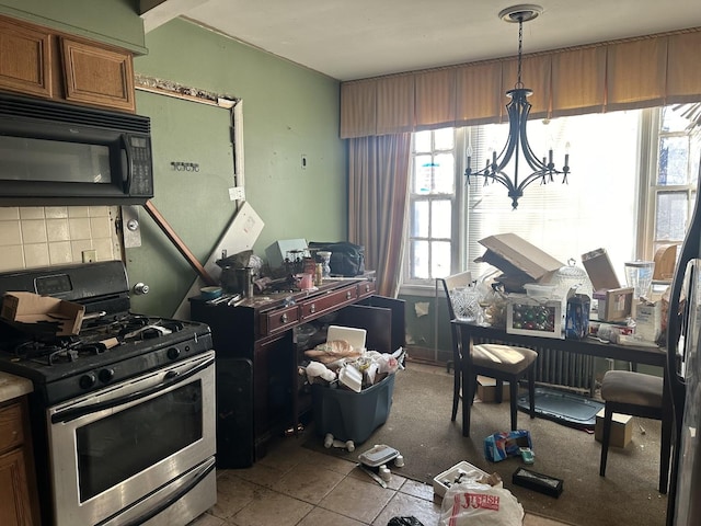 kitchen with light tile patterned floors, stainless steel range with gas stovetop, backsplash, a notable chandelier, and pendant lighting