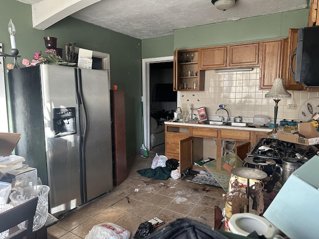 kitchen featuring stainless steel fridge with ice dispenser, backsplash, light tile patterned flooring, a textured ceiling, and sink