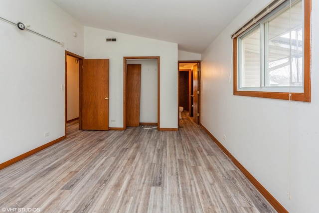 unfurnished bedroom with a closet, light hardwood / wood-style flooring, and lofted ceiling