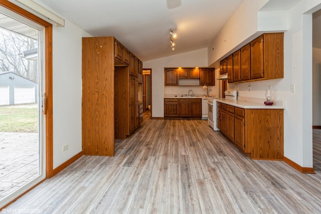 kitchen with light hardwood / wood-style flooring, white appliances, sink, and vaulted ceiling