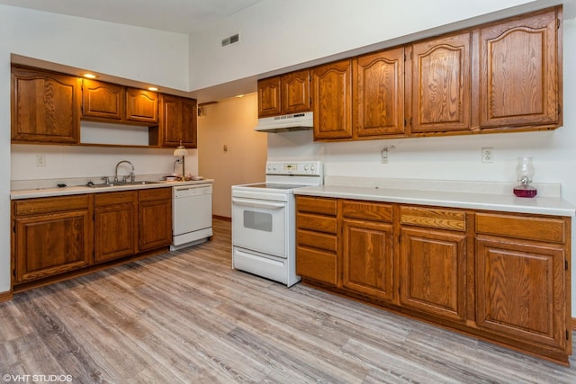 kitchen featuring sink, high vaulted ceiling, white appliances, and light hardwood / wood-style flooring