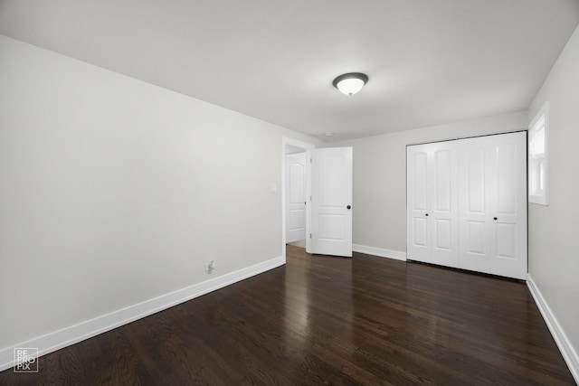 unfurnished bedroom featuring a closet, dark wood finished floors, and baseboards