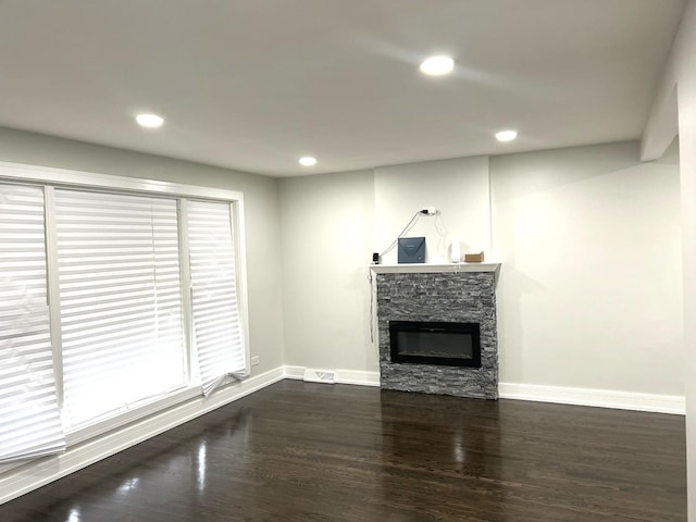 unfurnished living room with dark wood finished floors, recessed lighting, visible vents, a stone fireplace, and baseboards