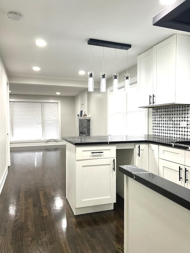 kitchen featuring tasteful backsplash, white cabinets, dark countertops, dark wood-style floors, and decorative light fixtures