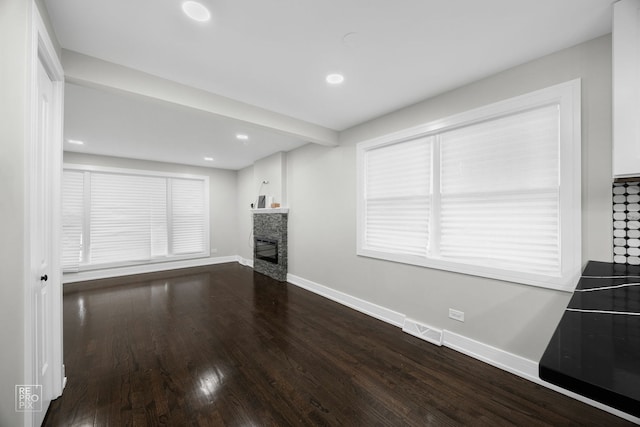 living area featuring visible vents, baseboards, wood finished floors, a stone fireplace, and recessed lighting