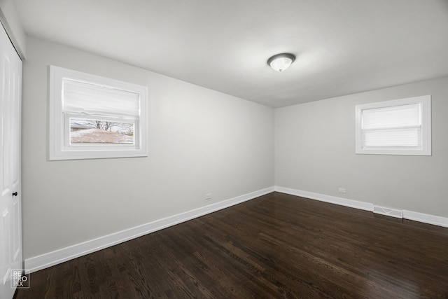 spare room with visible vents, dark wood finished floors, and baseboards