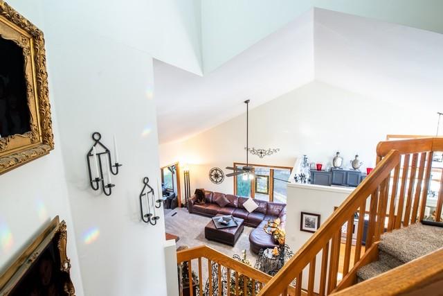 living room with carpet floors, high vaulted ceiling, and ceiling fan