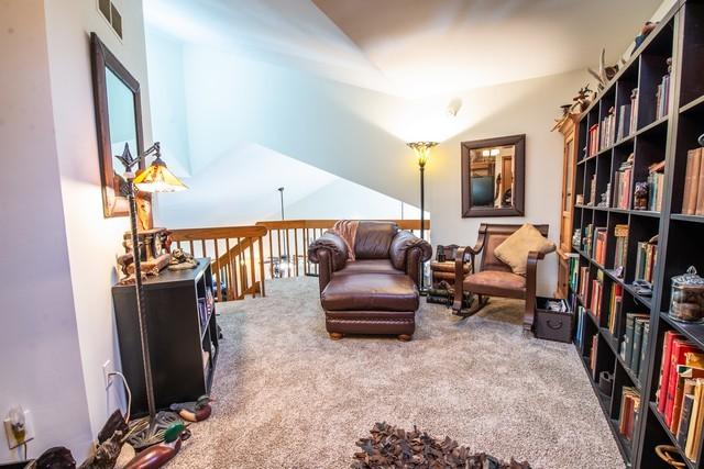 sitting room featuring carpet floors and vaulted ceiling