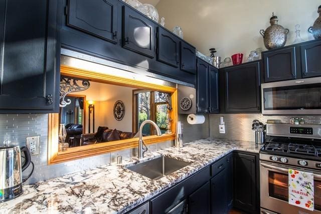 kitchen featuring backsplash, sink, vaulted ceiling, blue cabinetry, and appliances with stainless steel finishes