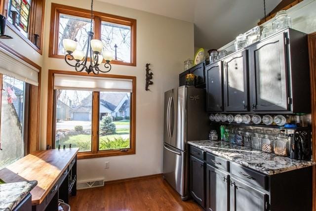 kitchen with light stone counters, dark wood-type flooring, pendant lighting, and a notable chandelier