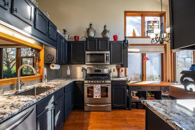 kitchen featuring sink, dark wood-type flooring, stainless steel appliances, backsplash, and a chandelier