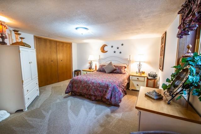 bedroom with a textured ceiling, light colored carpet, and a closet