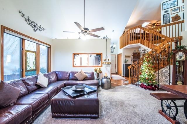 carpeted living room featuring ceiling fan and a high ceiling