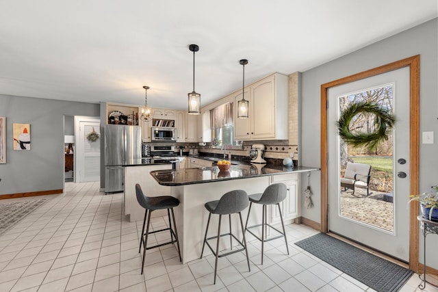 kitchen featuring backsplash, light tile patterned flooring, pendant lighting, and appliances with stainless steel finishes