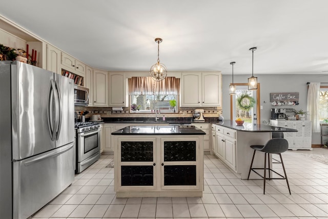 kitchen with appliances with stainless steel finishes, decorative light fixtures, a kitchen island, and cream cabinets