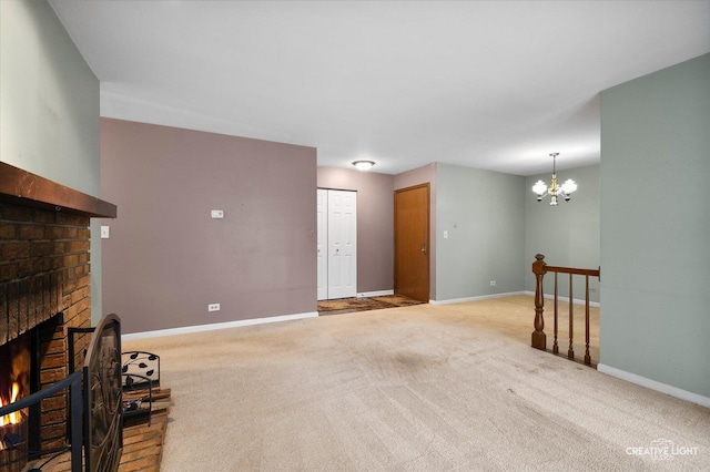 unfurnished living room featuring an inviting chandelier, light colored carpet, and a brick fireplace