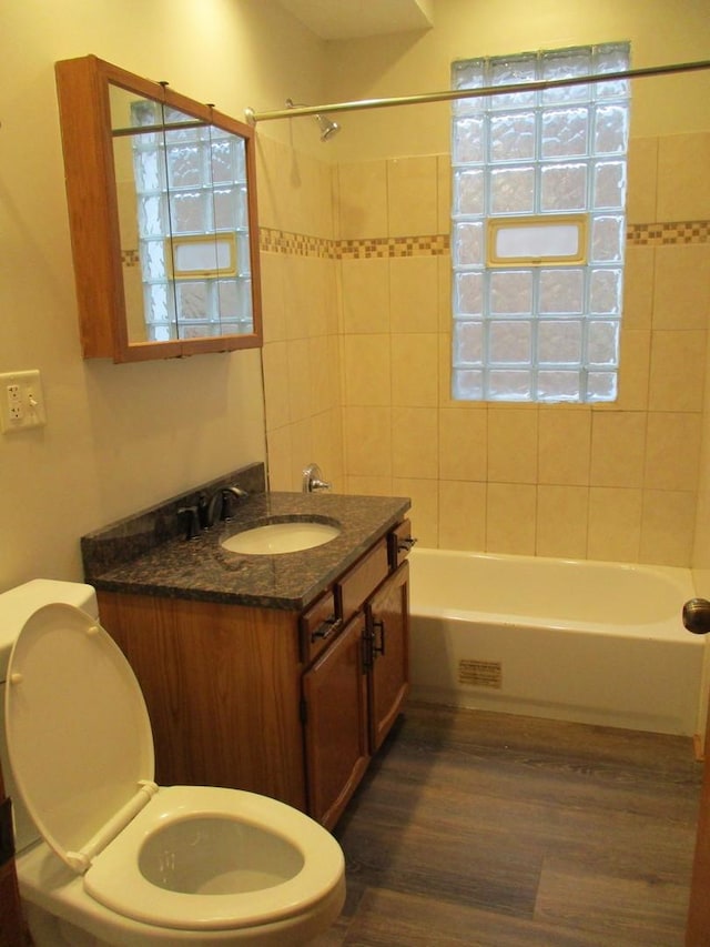 full bathroom featuring tiled shower / bath combo, toilet, wood-type flooring, and vanity