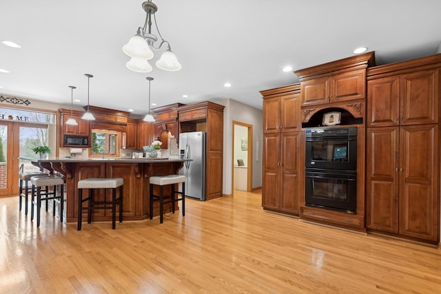 kitchen with black appliances, a kitchen island, decorative light fixtures, light hardwood / wood-style floors, and a chandelier