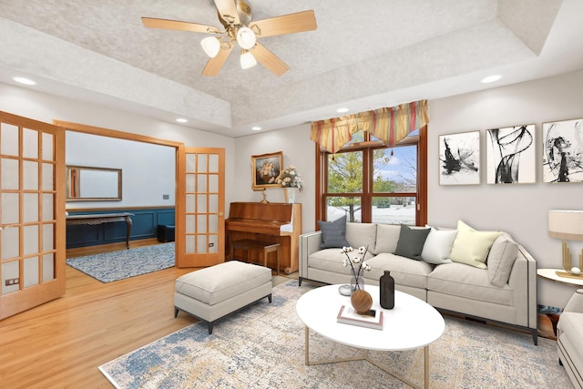 living room with french doors, a tray ceiling, ceiling fan, and hardwood / wood-style floors