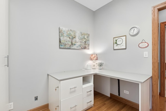 unfurnished office featuring light wood-type flooring and built in desk