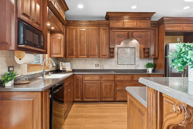 kitchen with tasteful backsplash, sink, black appliances, and light hardwood / wood-style flooring