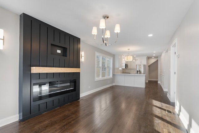 unfurnished living room with a fireplace, dark hardwood / wood-style flooring, and a chandelier