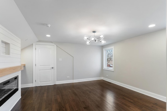 unfurnished living room featuring a notable chandelier, vaulted ceiling, and dark hardwood / wood-style floors