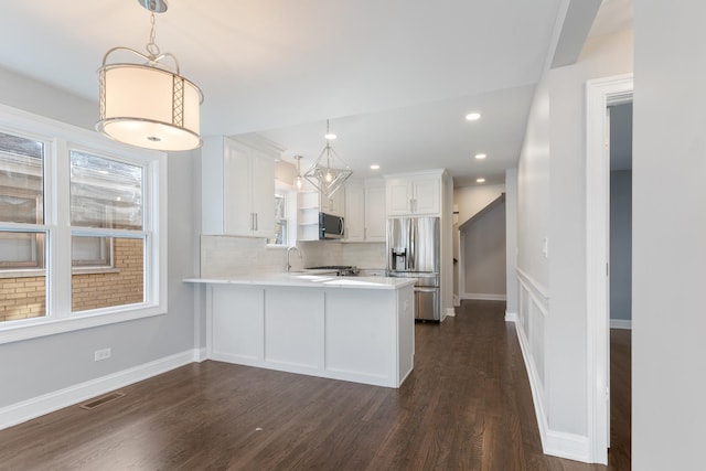 kitchen featuring decorative light fixtures, white cabinetry, backsplash, kitchen peninsula, and stainless steel appliances