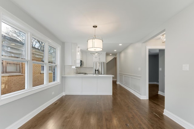 kitchen with stainless steel refrigerator with ice dispenser, tasteful backsplash, white cabinets, dark hardwood / wood-style flooring, and kitchen peninsula