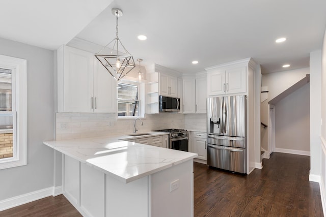 kitchen featuring white cabinetry, appliances with stainless steel finishes, kitchen peninsula, and decorative light fixtures