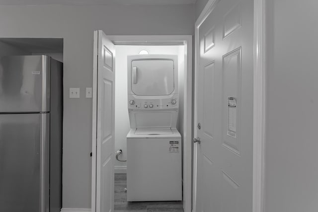 washroom with wood-type flooring and stacked washer and dryer