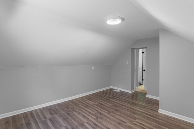 bonus room with dark hardwood / wood-style flooring and vaulted ceiling