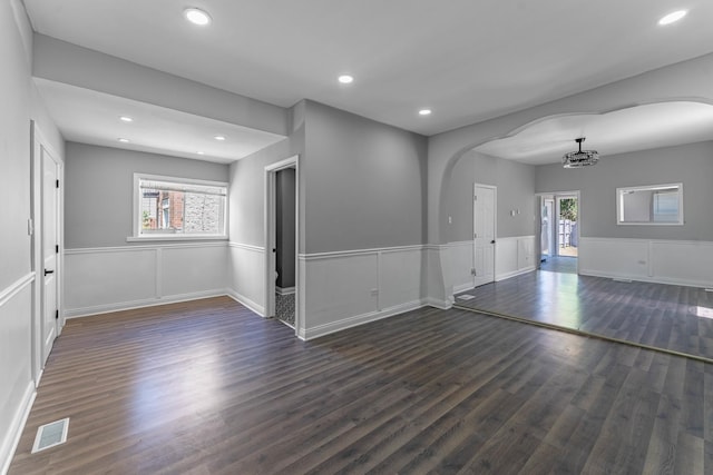 empty room featuring dark hardwood / wood-style floors, a healthy amount of sunlight, and a chandelier