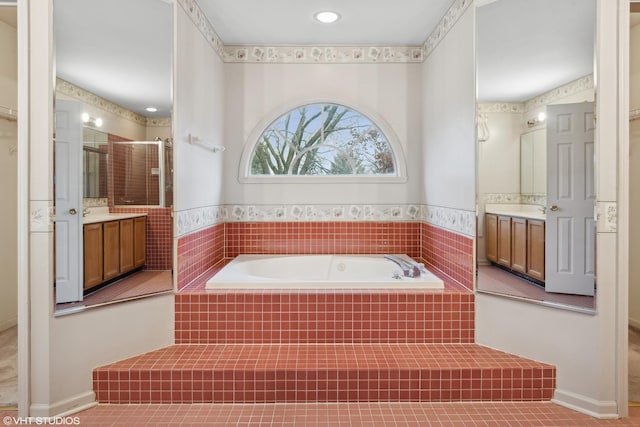 bathroom featuring tile patterned flooring, vanity, and a relaxing tiled tub