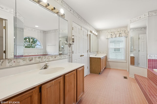 bathroom featuring tile patterned flooring, vanity, and a relaxing tiled tub