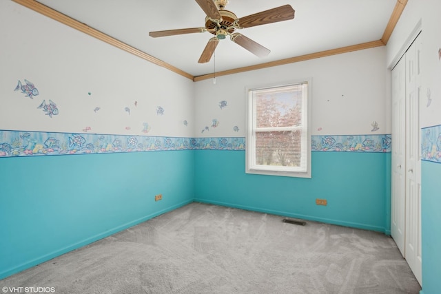 spare room with ceiling fan, ornamental molding, and carpet flooring